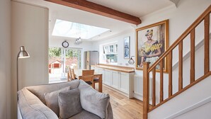 A modern living room with a grey sofa, wooden flooring, and a staircase with a wooden railing. - Host Stay Bankside Cottage (Saltburn-by-the-Sea)