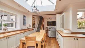 A modern kitchen with a wooden dining table, white cabinetry, and a skylight. - Host Stay Bankside Cottage (Saltburn-by-the-Sea)