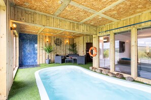 A wooden cabin with a hot tub, a seating area with a table and chairs, and a large window with a view. - Host Stay Crackin View (Hexham)