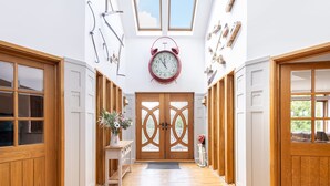 Un couloir avec des portes en bois, une horloge centrale et une lucarne.