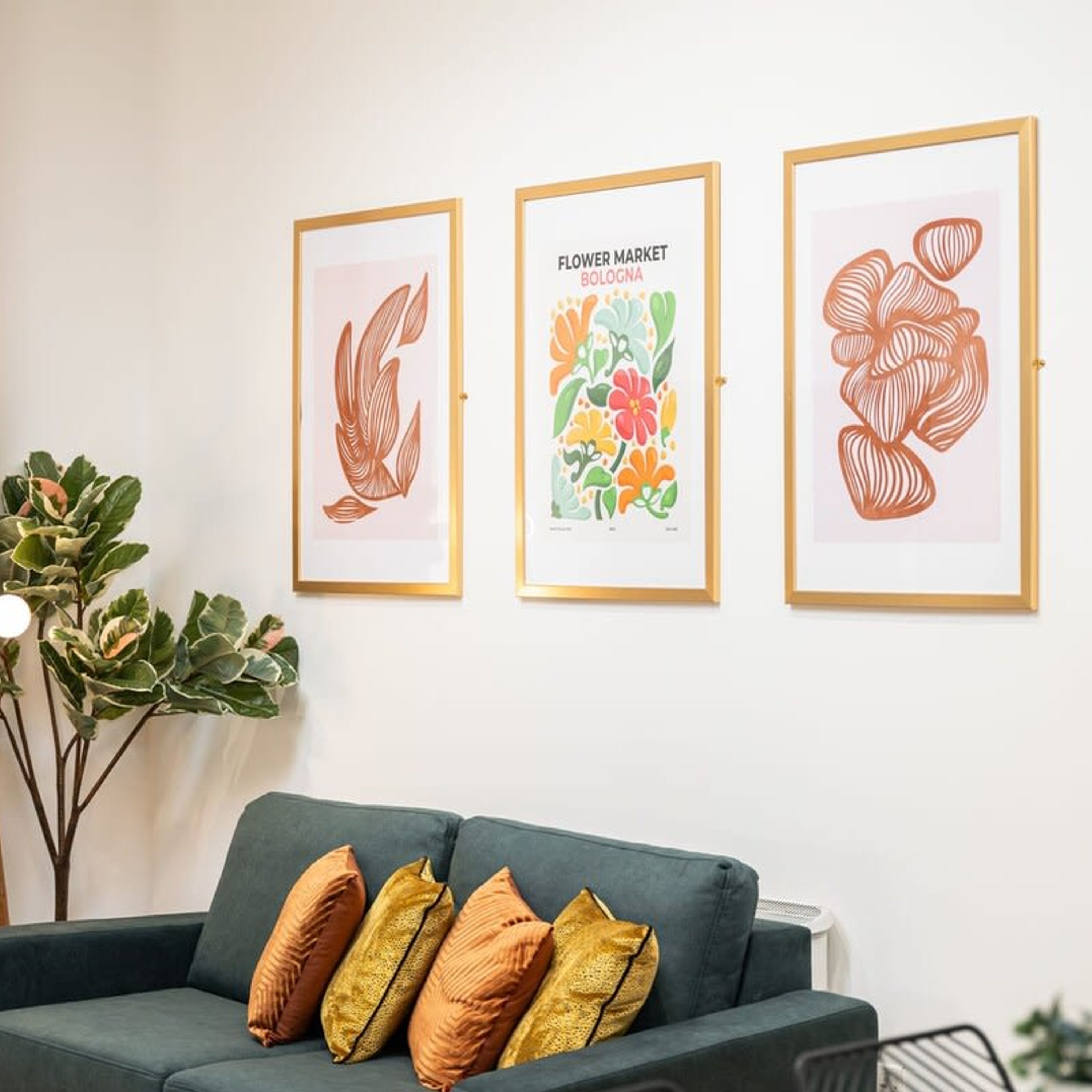 A room with a green sofa and three framed artworks on the wall.