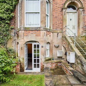 A historic building with a stone facade, a white door, and a small garden area. - Host Stay The Den (Whitby)