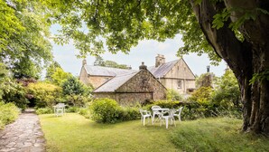 A stone house with a stone roof, surrounded by a well-maintained lawn and a stone pathway. - Host Stay Upper Lodge (Alnwick)