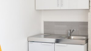 Una cocina compacta con lavavajillas integrado, un lavabo y un salpicadero de azulejos.