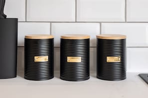 Three black cylindrical containers with wooden lids and brass labels on a countertop. - Host Stay Princes Place Hideaway I (Liverpool)