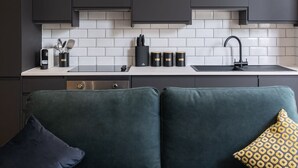 A modern kitchen with dark cabinets, a white tiled backsplash, and a black faucet. - Host Stay Princes Place Hideaway I (Liverpool)