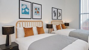 A hotel room with two beds, a nightstand with a lamp, and artwork on the wall. - Host Stay Princes Place Hideaway III (Liverpool)