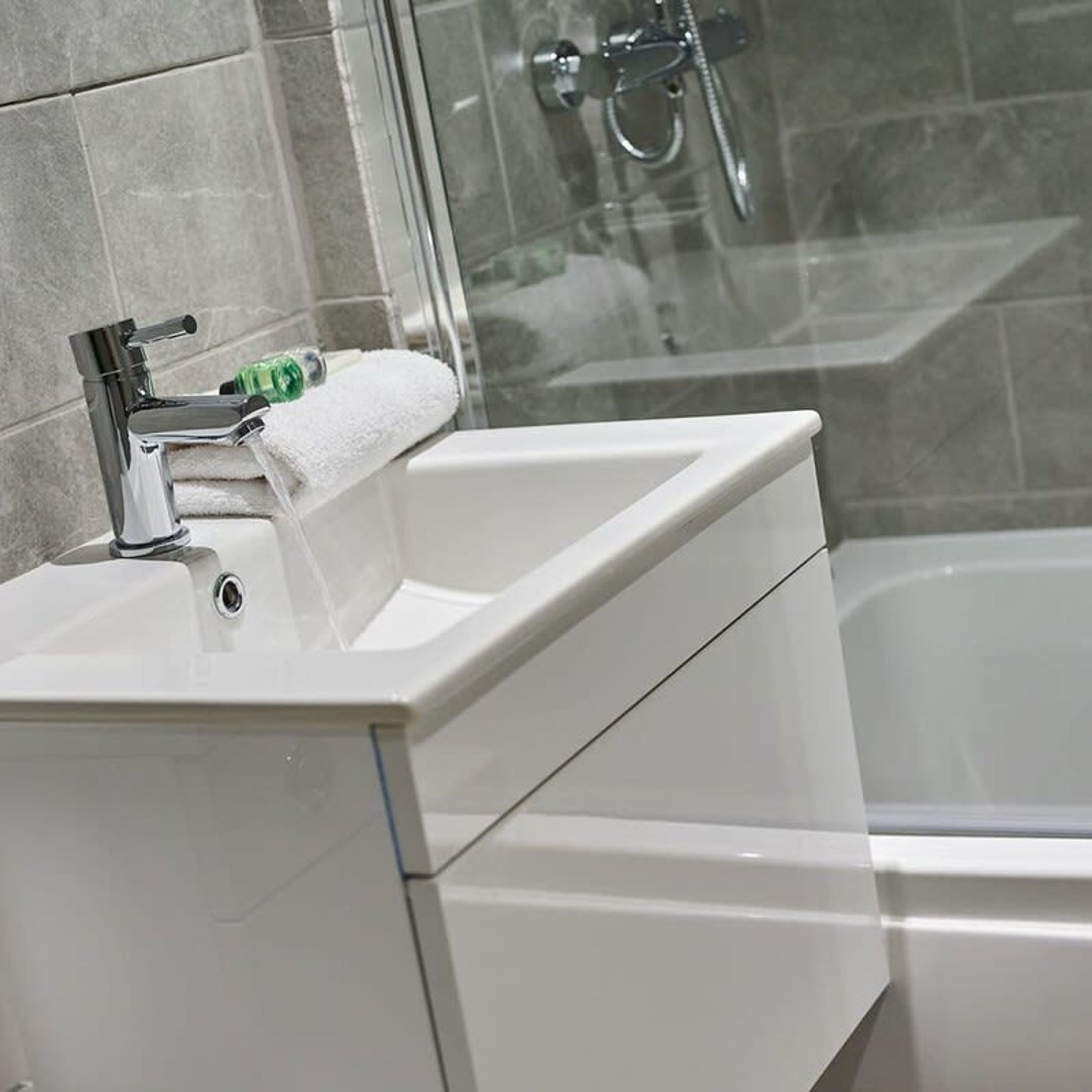 Une salle de bain avec un lavabo blanc, une serviette et un espace douche.