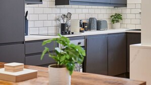 A modern kitchen with dark cabinets, white tiled backsplash, and a wooden countertop. - Host Stay Princes Place Hideaway III (Liverpool)