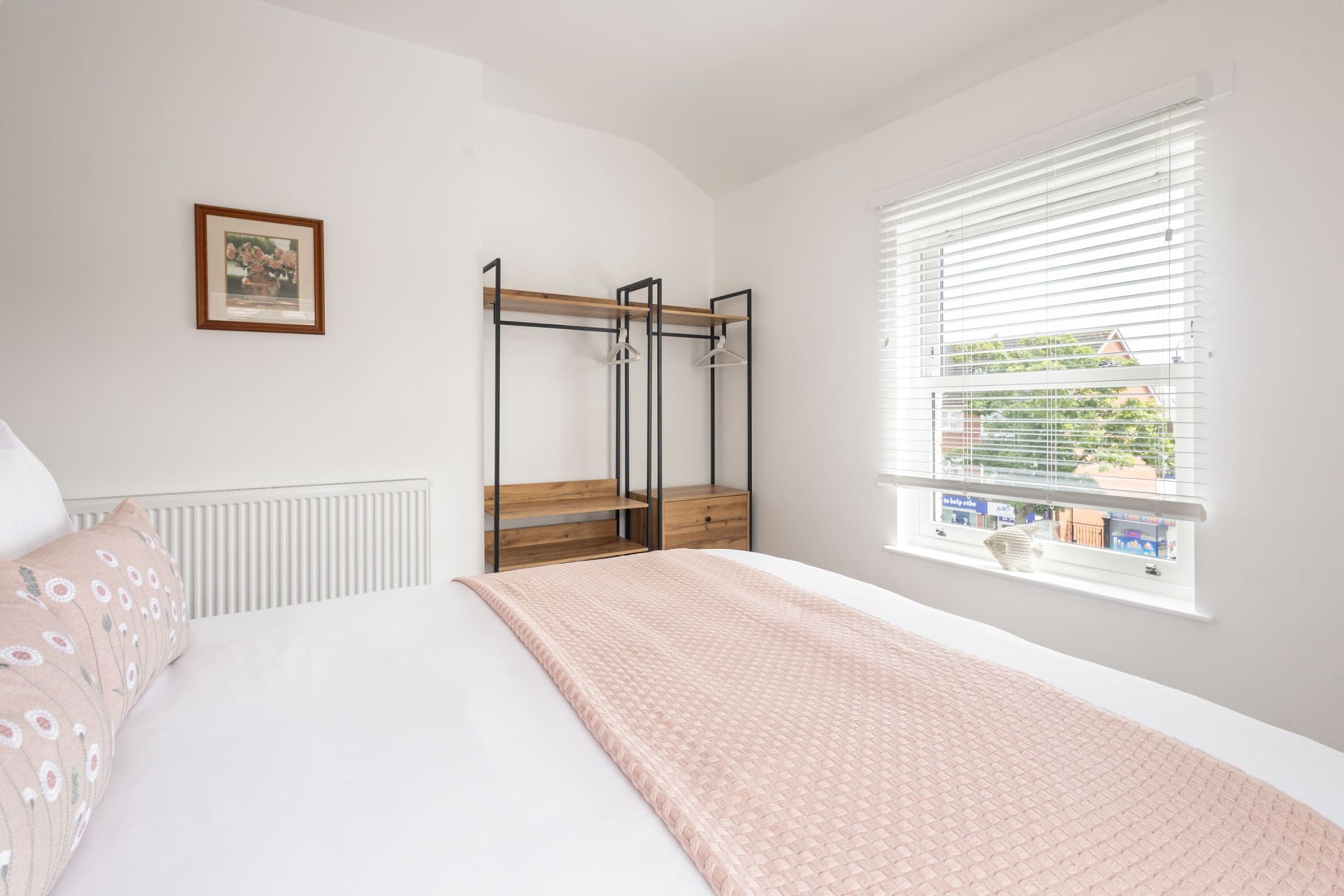 Une chambre à coucher avec un lit, une armoire, une fenêtre et un radiateur.