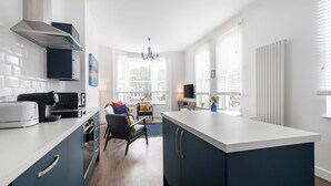 A modern kitchen with a central island, built-in appliances, and a dining area with a sofa and table. - Host Stay Sanderling Chase (Scarborough)