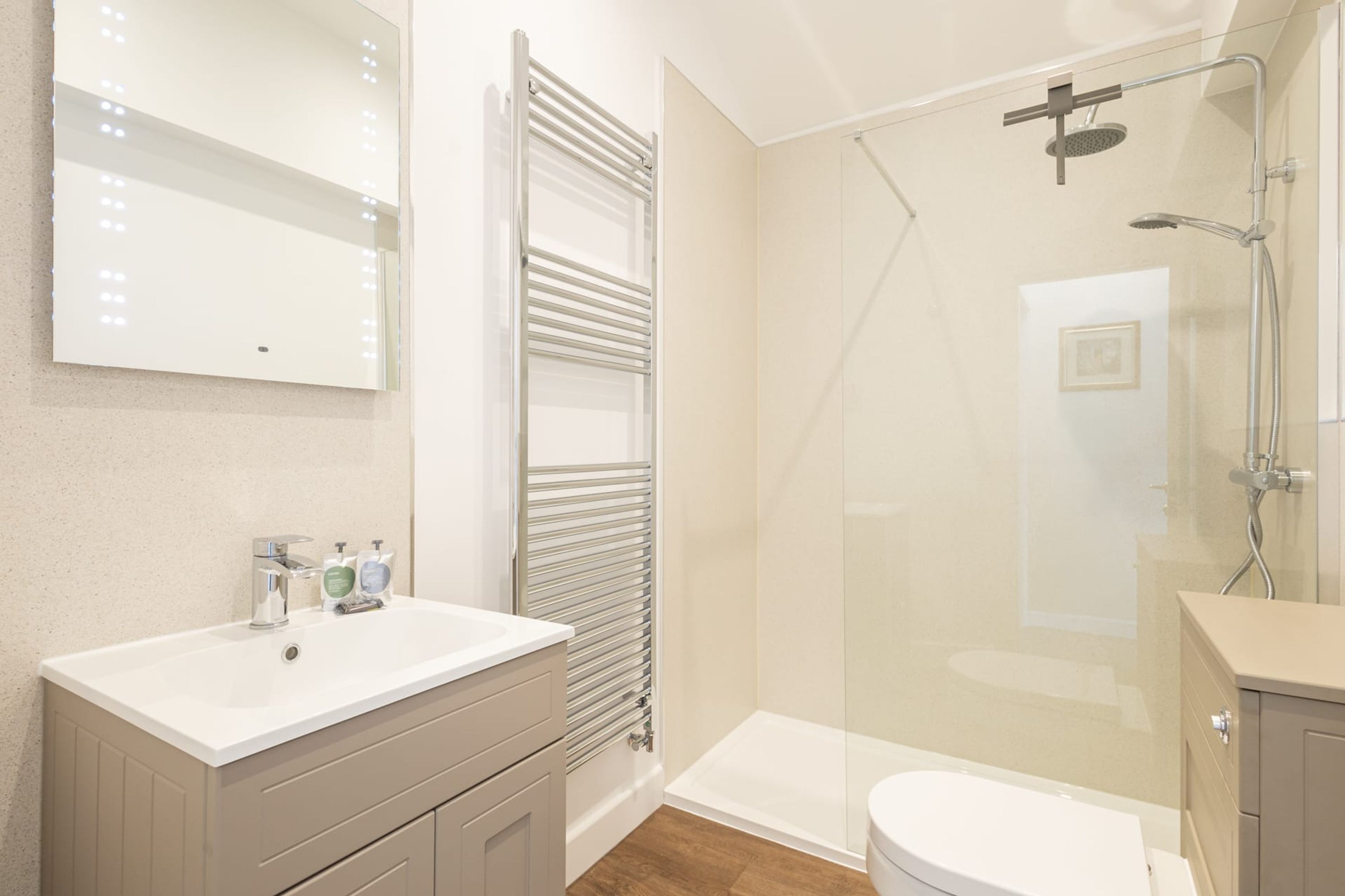 A modern bathroom with a glass-enclosed shower, a vanity with a mirror, and a toilet.
