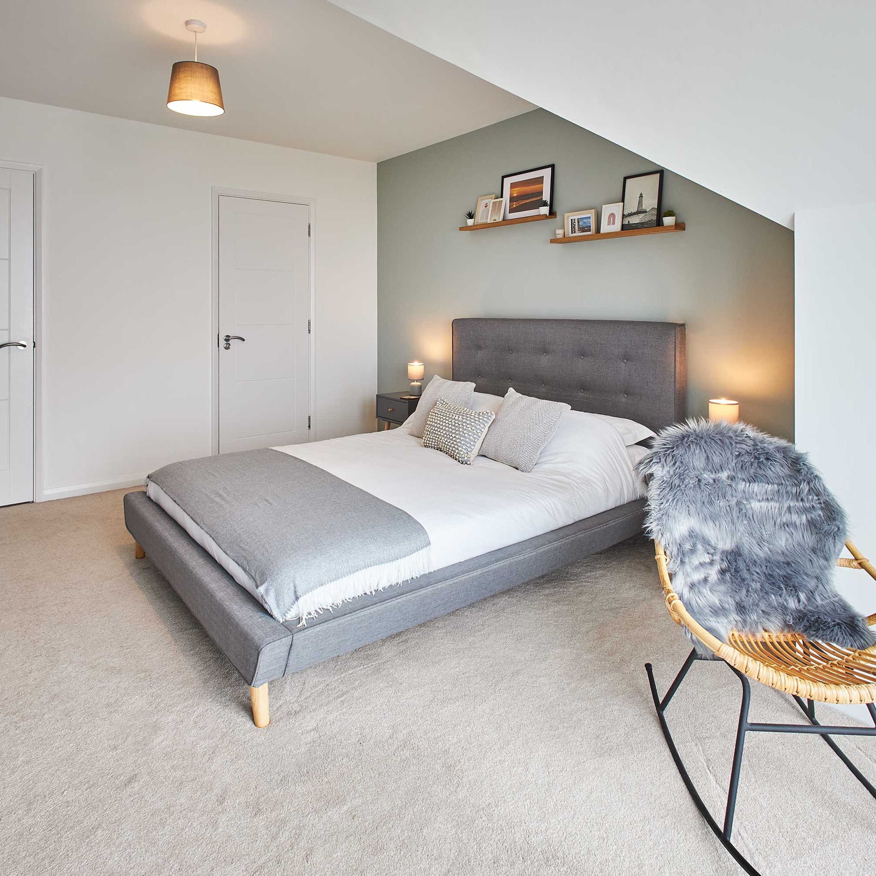 Un dormitorio con una cama, una silla y una pared decorada con cuadros.