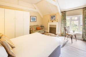A bedroom with a large bed, a sofa, a fireplace, and a window with curtains. - Host Stay Upper Lodge (Alnwick)
