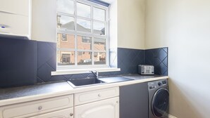 Een kleine keuken met een raam, een wasmachine en een broodrooster.