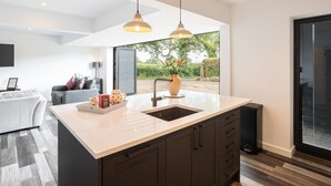 Una cucina moderna con un'isola grande, mobili scuri e luci a sospensione.