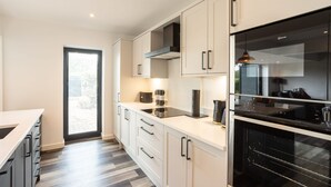 Una cucina moderna con mobili bianchi, un forno nero e una finestra che lascia entrare luce naturale.