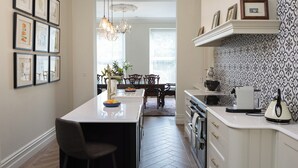 A modern kitchen with a central island, a dining area with a chandelier, and a patterned backsplash.