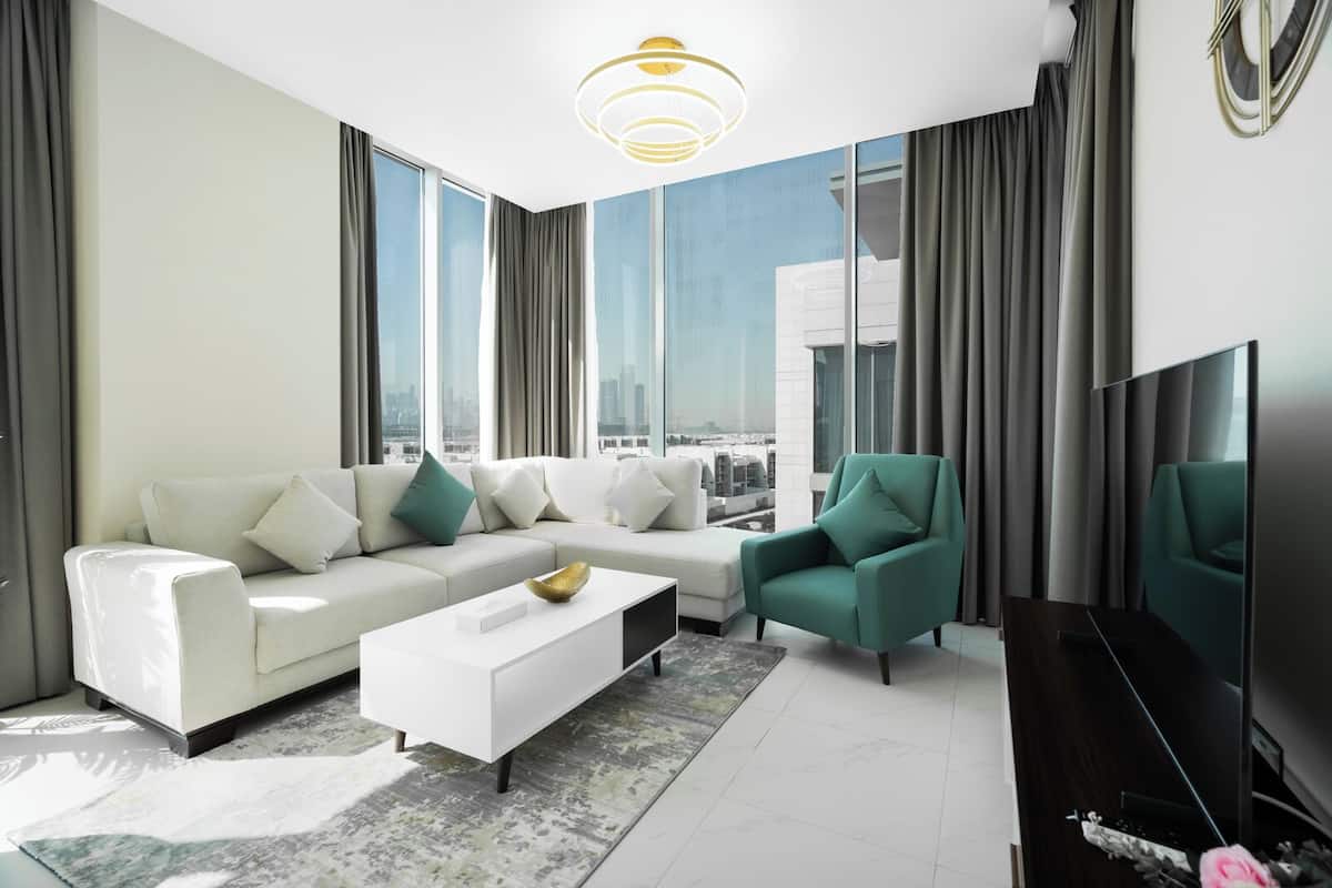 A modern living room with a white sofa, teal armchair, and a flat-screen TV.