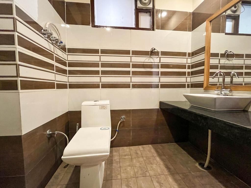 A bathroom with a toilet, sink, and mirror.