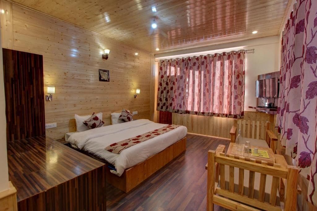 A wooden-paneled room with a bed, a wooden bench, and a small table.