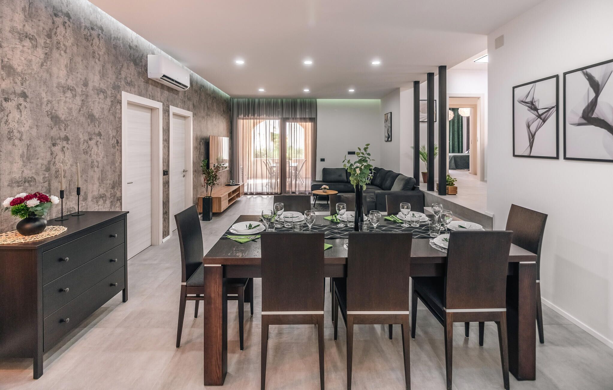 Een moderne eetruimte met een lange tafel voor zes personen, omringd door donkerhouten stoelen.