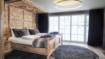En seng med træramme og sengegavl, et stort vindue og en rund lampe.
