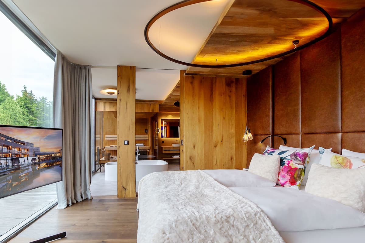 Une chambre d’hôtel moderne avec un grand lit, une télévision et une vue sur un immeuble par la fenêtre.