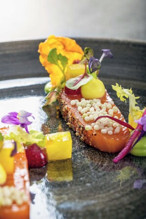 A dish with salmon, vegetables, and a flower garnish on a plate. - Wellness & Naturresort Reischlhof (Wegscheid)