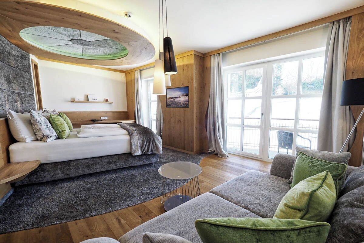 Un salon moderne avec un canapé, une table basse ronde et un lit doté d’une tête de lit.