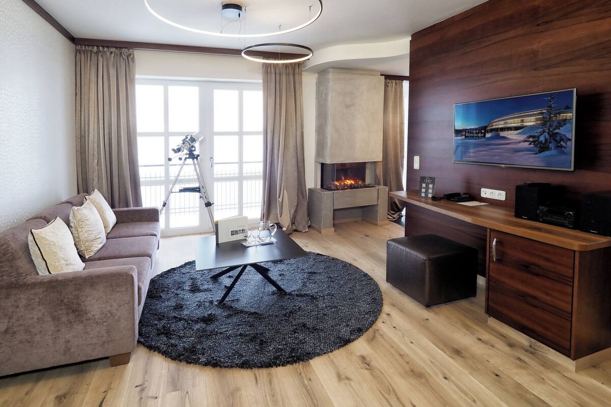 Un salon moderne avec une cheminée, un canapé, une table basse et un téléviseur fixé au mur.