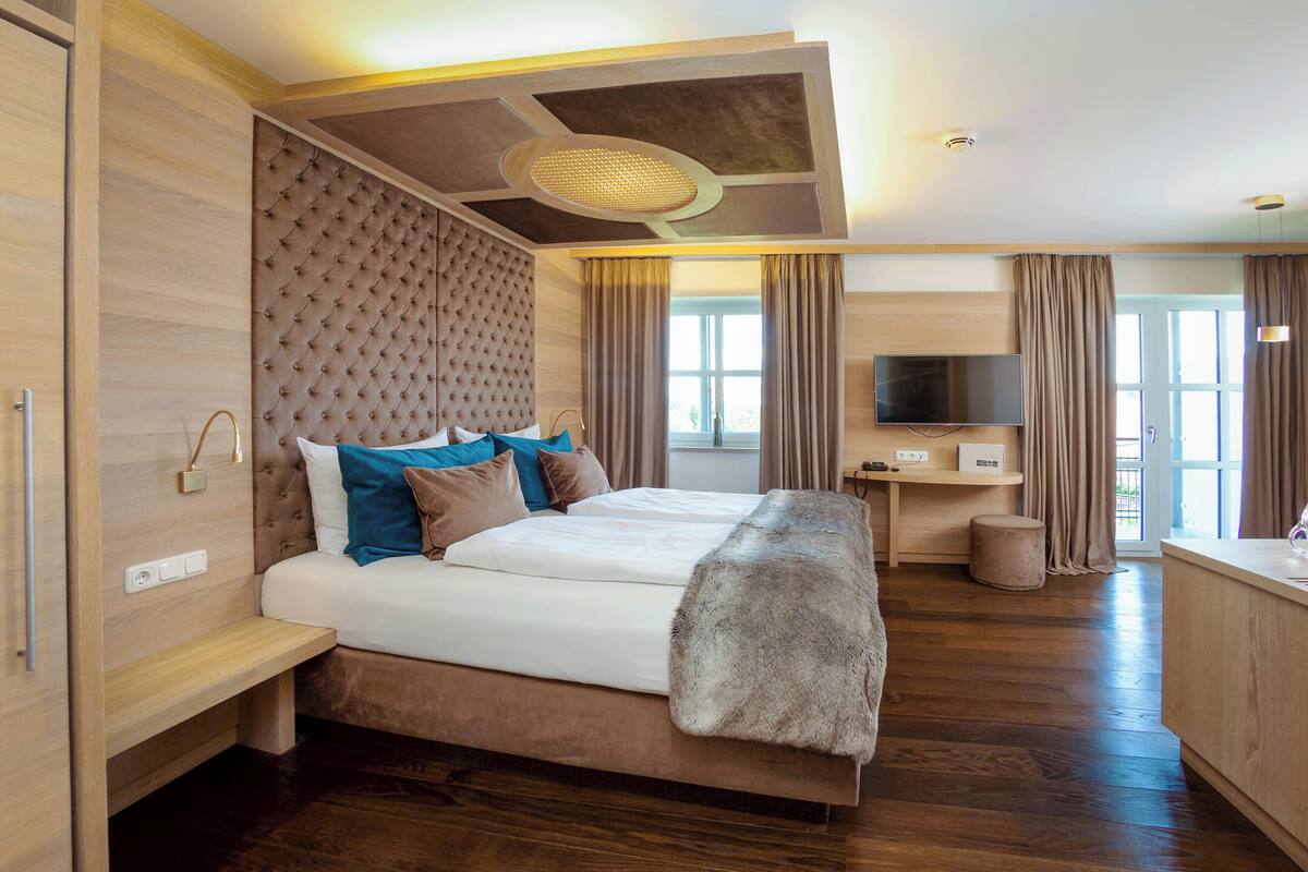Une chambre d’hôtel moderne dotée d’un grand lit, d’une télévision à écran plat, d’un bureau et d’une fenêtre avec des rideaux.