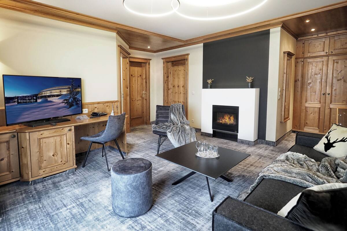 Un salon moderne avec une cheminée, des meubles en bois et un téléviseur.
