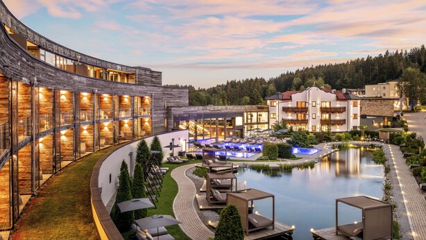 Un resort con un edificio curvo, piscina y zonas de estar al aire libre.