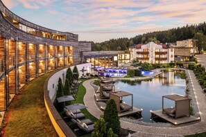 Un complexe hôtelier doté d’un bâtiment aux lignes courbes, d’une piscine et d’espaces de détente en plein air.