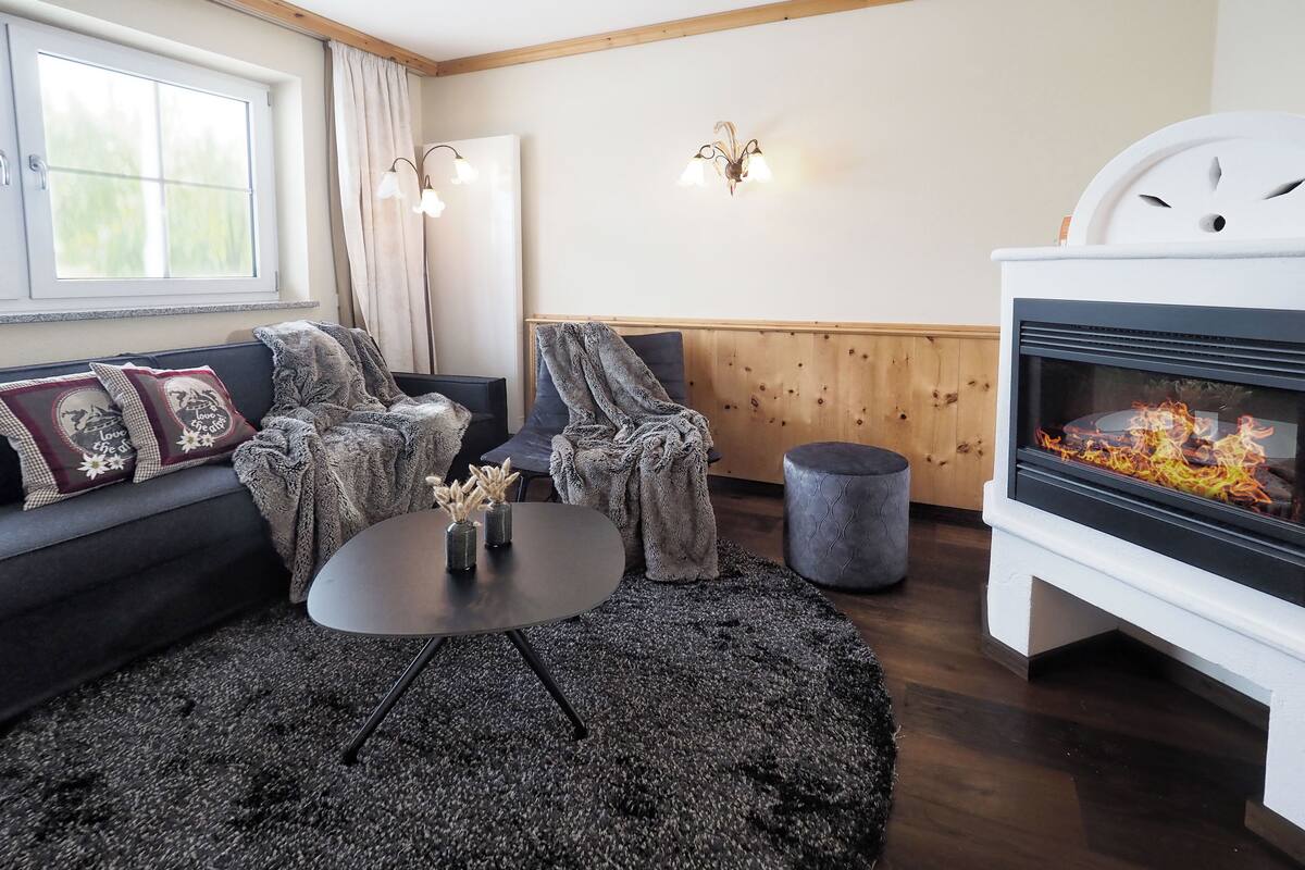 Un salon chaleureux avec une cheminée, un canapé agrémenté de coussins décoratifs, une table basse ronde et un tapis.