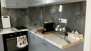 A kitchen with grey cabinets, a built-in oven, a coffee maker, and a marble countertop. - ENE'S Mykonos (Mykonos)