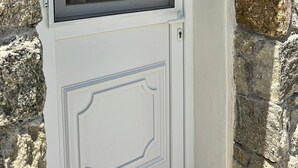 A white door with a window above it, set against a stone wall. - ENE'S Mykonos (Mykonos)