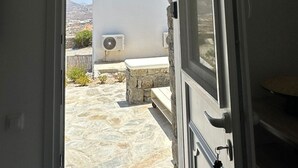 An open door leading to a stone-floored patio with a white wall and air conditioning unit above. - ENE'S Mykonos (Mykonos)