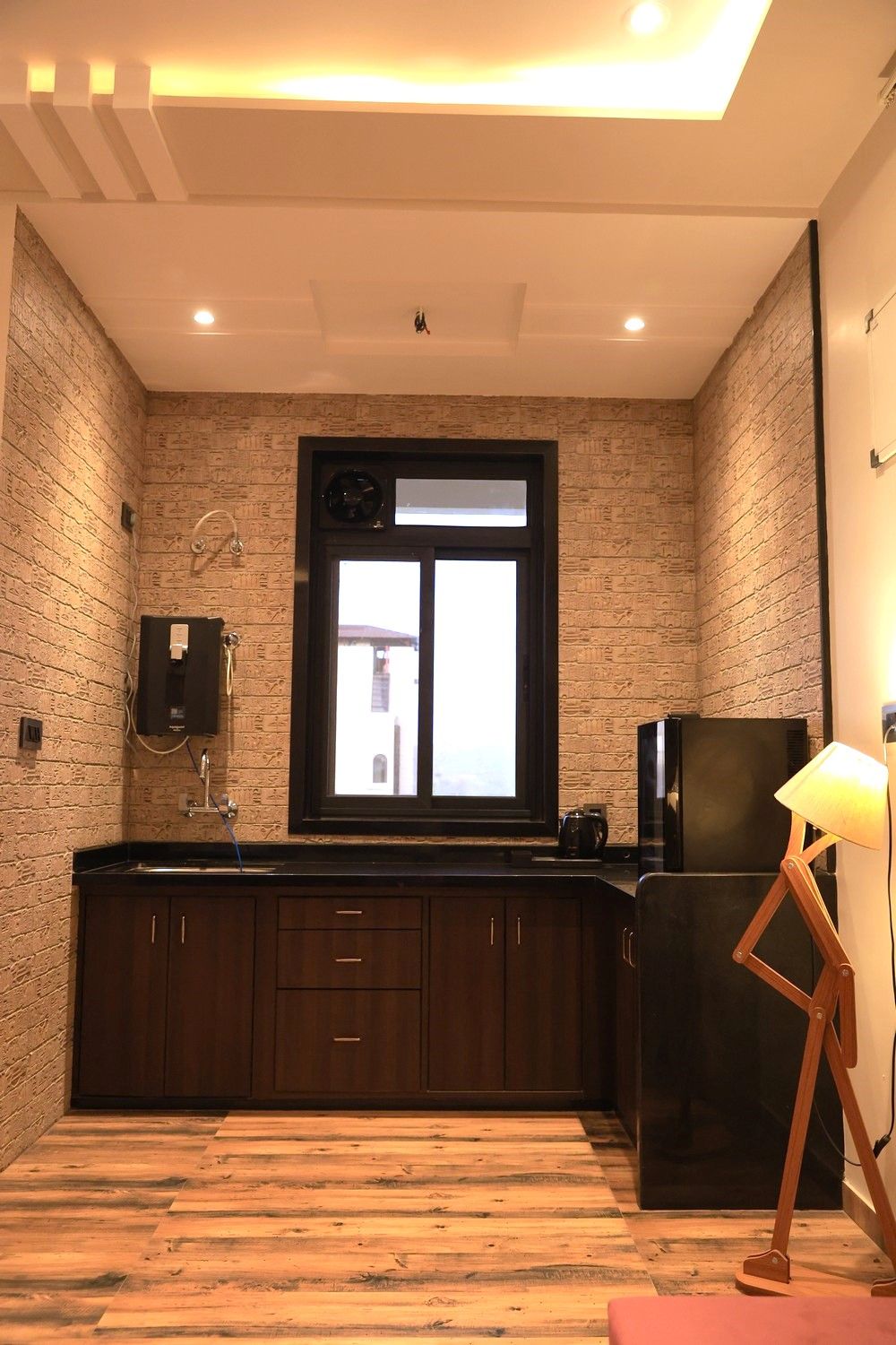 Una cocina moderna con pared de ladrillo, armarios de madera, un refrigerador negro y una ventana con vistas.