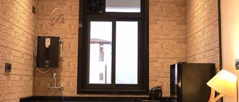 Una cocina moderna con pared de ladrillo, armarios de madera, un refrigerador negro y una ventana con vistas.