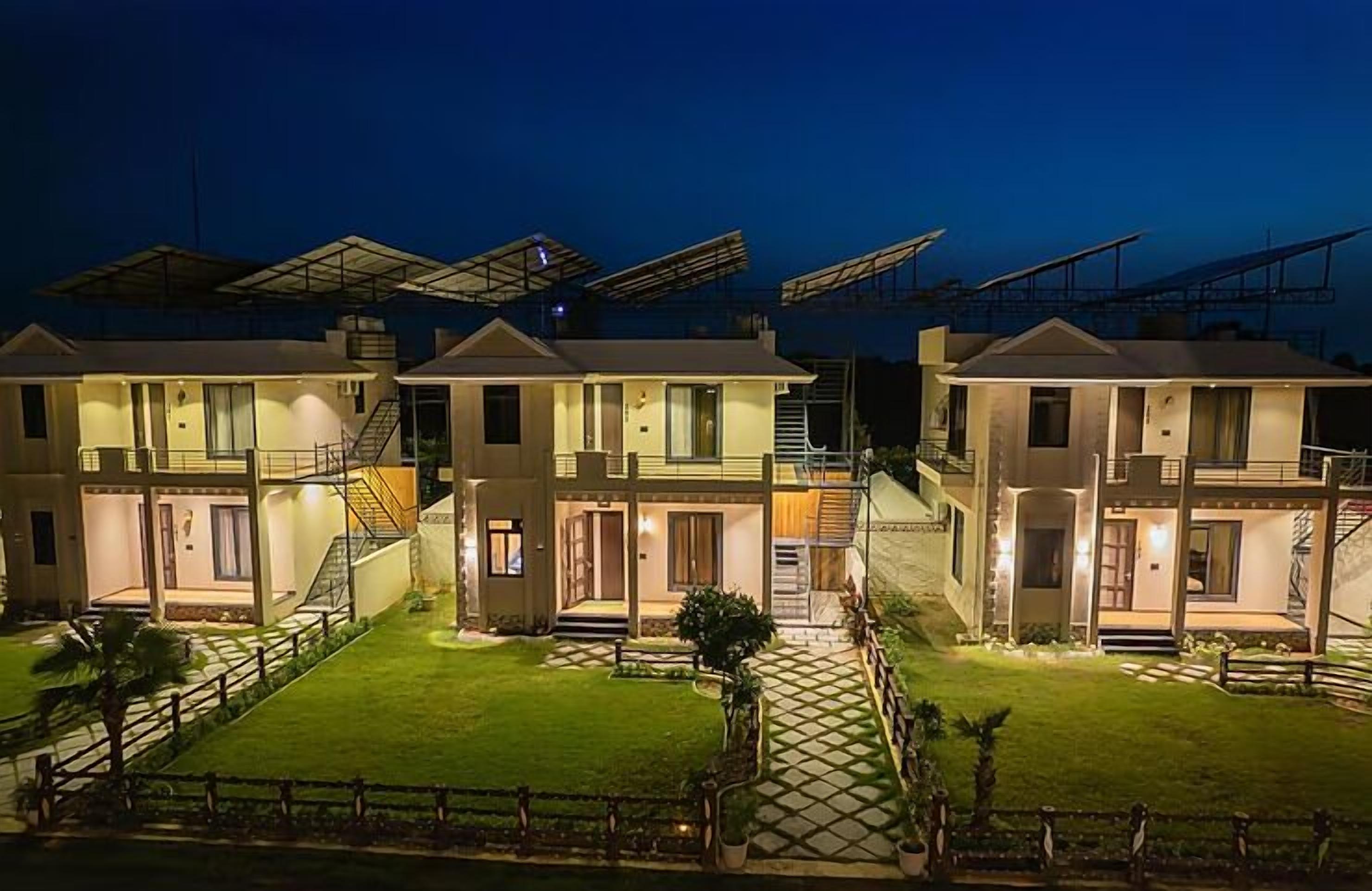Fila de casas modernas de dos pisos con paneles solares en los techos, césped cuidado y entrada protegida por una reja.