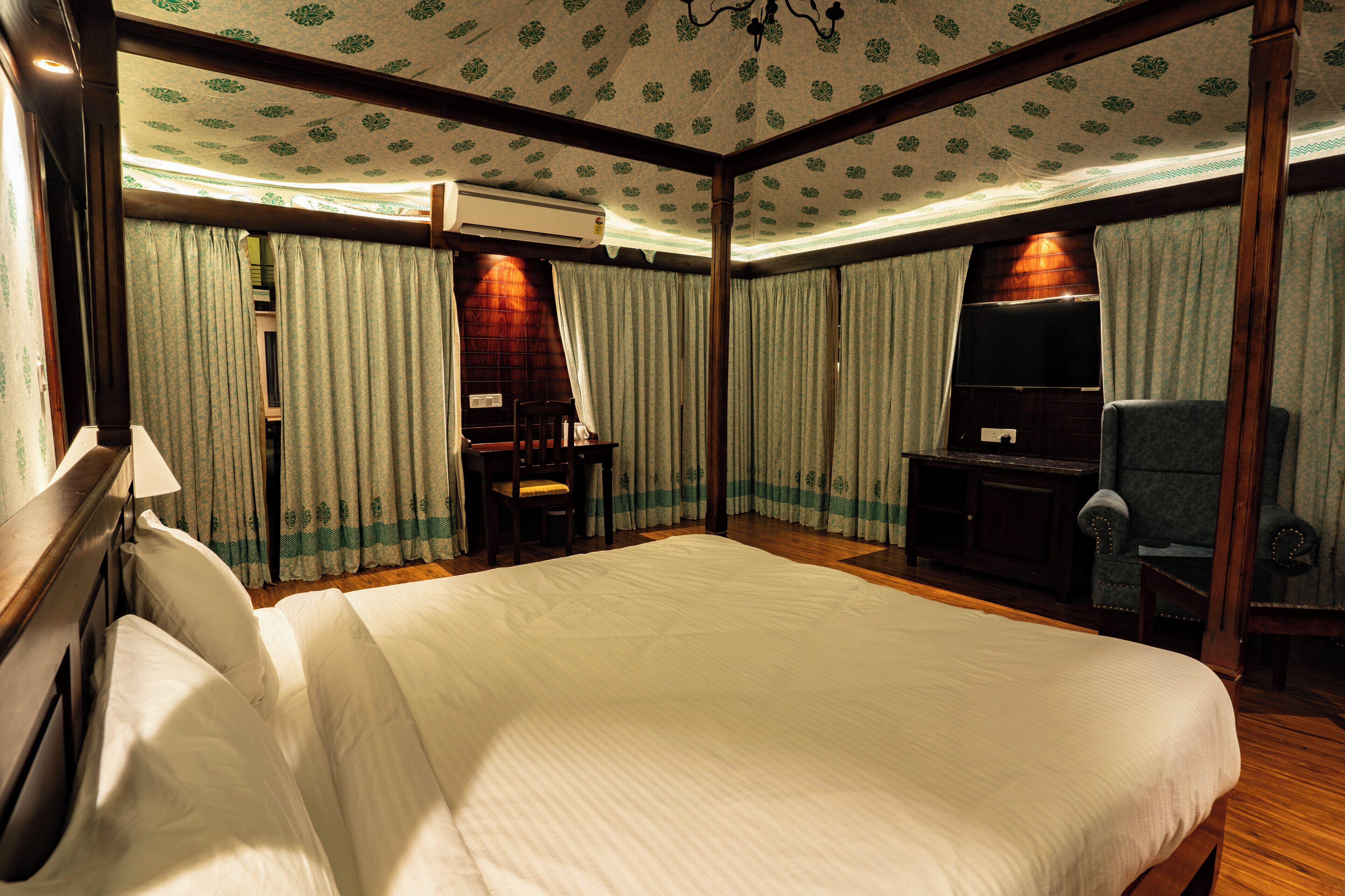 A hotel room with a large bed, a desk, a chair, and a television.
