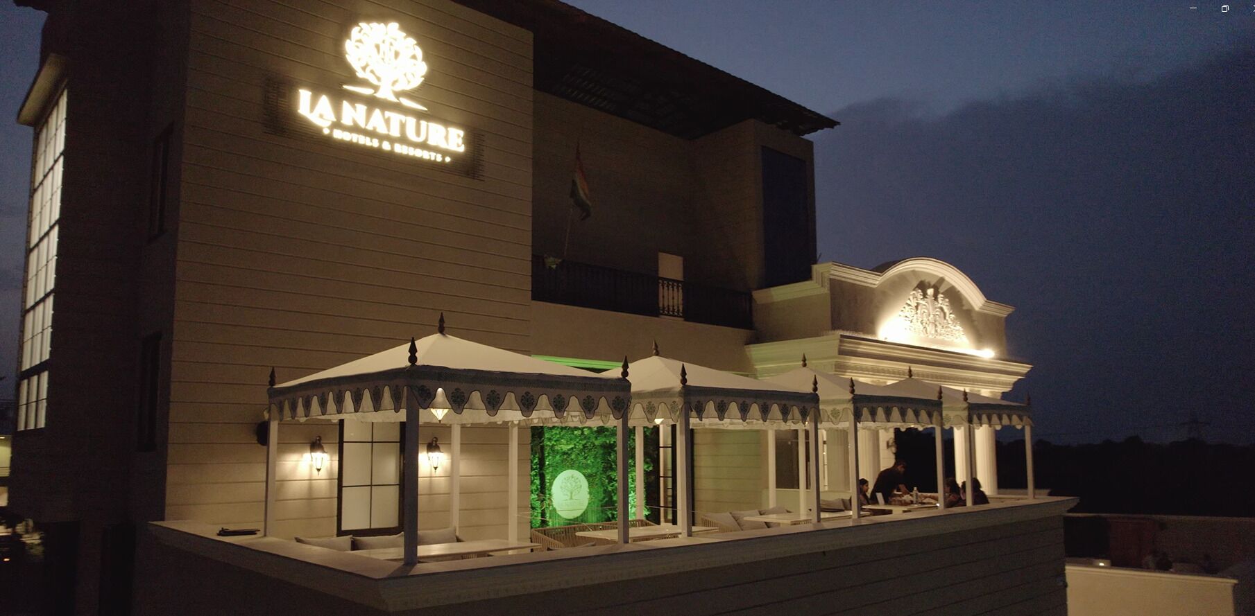 Un edificio con un letrero que dice "LA NATURE" y un área de estar al aire libre cubierta.