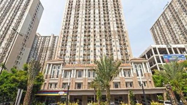 A high-rise residential building with multiple balconies, surrounded by other tall buildings and greenery. - Hotel O Dealova Room (Gunung Putri)