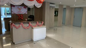A reception desk with a banner, a number '78', and a decorative garland. - Hotel O Dealova Room (Gunung Putri)