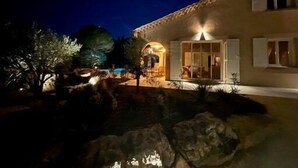 A well-lit building with a patio area, large windows, and a stone pathway.