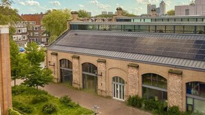 A building with a brick facade, large windows, and a flat roof with solar panels. - AMSTERDAM TOWN HOUSE WITH PRIVATE GARDEN & PARKING (Amsterdam)