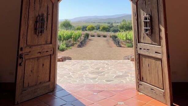 An arched doorway leading to an outdoor vineyard view. - Hacienda Maria Trinidad (Valle de Guadalupe)