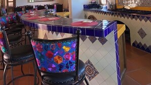 A restaurant with a central island, bar stools, and hanging pendant lights. - Hacienda Maria Trinidad (Valle de Guadalupe)